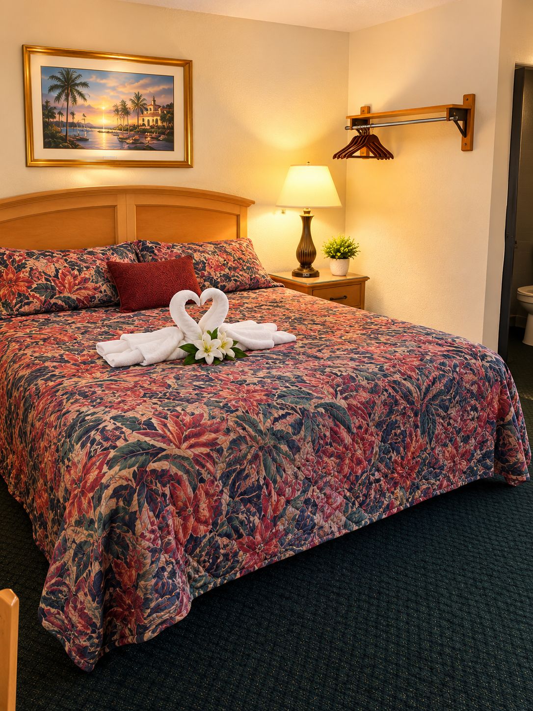 A hotel room with a large bed, a nightstand with a lamp, a framed picture on the wall, and a wooden headboard.