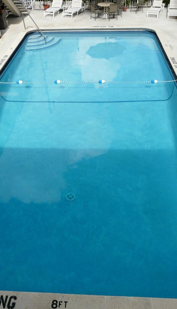 Una piscina al aire libre, sombrillas, sillones reclinables de piscina