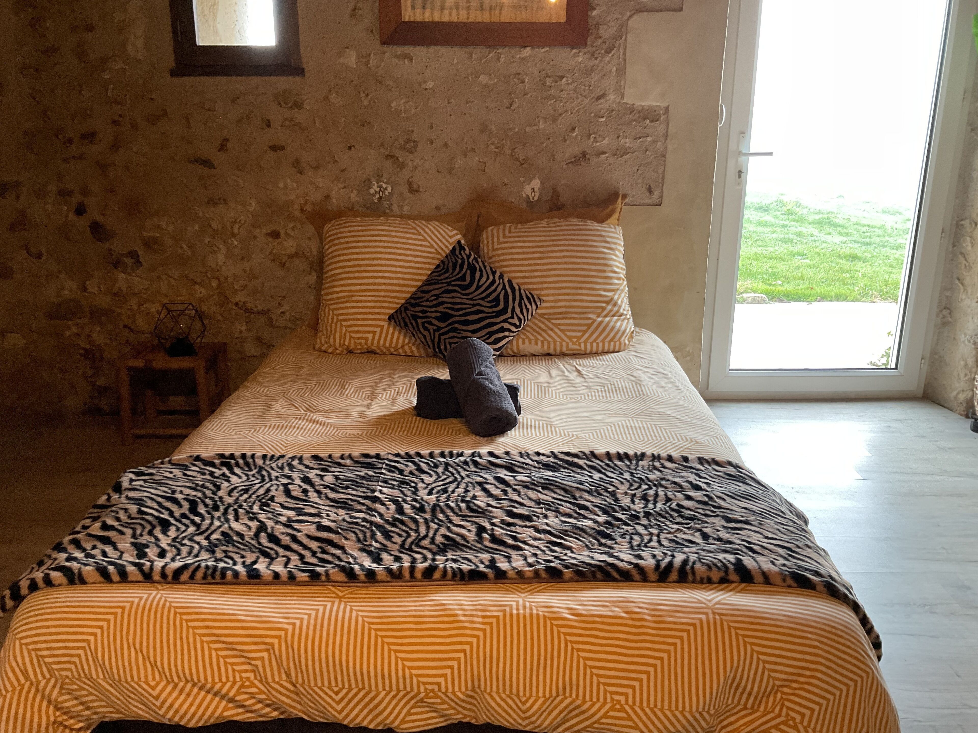 A bedroom with a bed, pillows, and a blanket.