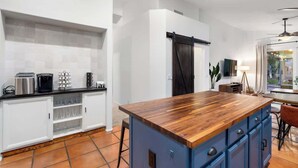A modern kitchen with white cabinets, a wooden island, and a dining area with a table and chairs. - Waterfront Villa with Pool Hot Tub Lounge area (Chandler)