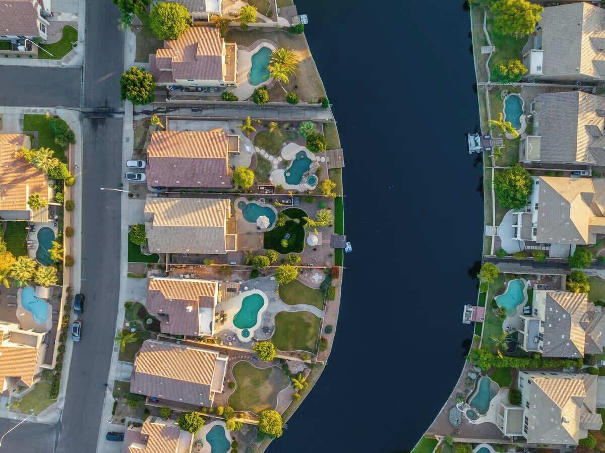 Une vue aérienne d’un quartier résidentiel composé de plusieurs maisons, chacune dotée d’une piscine et d’une allée incurvée.