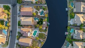 An aerial view of a residential area with multiple houses, each featuring a swimming pool and a curved driveway. - Waterfront Villa with Pool Hot Tub Lounge area (Chandler)