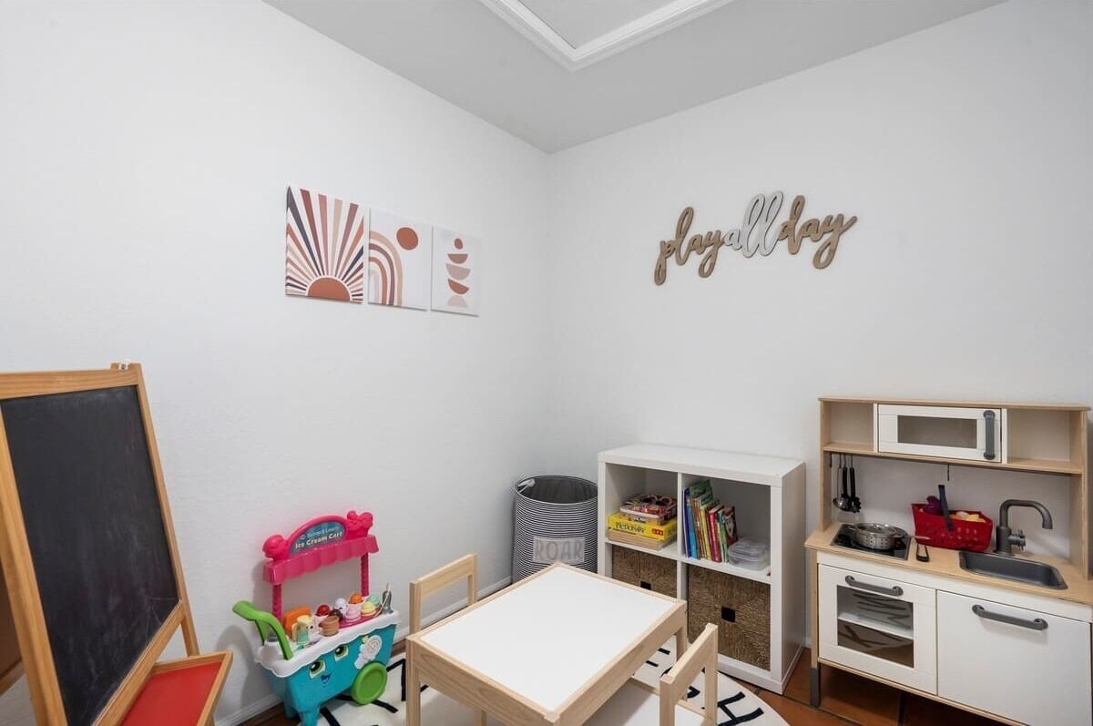 Une salle de jeux pour enfants avec un tableau noir, un chariot à glaces jouet et un espace de jeu.