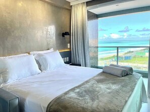 A hotel room with a large bed, a view of the ocean, and a balcony with a railing. - RN STUDIO - APTO 417 (Maceió)