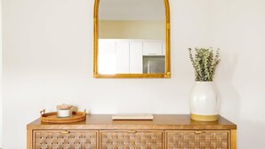 A wooden cabinet with woven drawers, a mirror, a vase with green foliage, and a tray with a container. - 6BR Villa w/ Pool, King Beds & Top Amenities! (Miami)