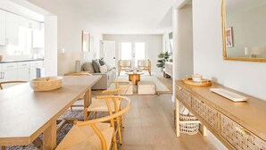 A modern kitchen with white cabinets, a dining area with a wooden table and chairs, and a living area with a sofa and chairs. - 6BR Villa w/ Pool, King Beds & Top Amenities! (Miami)