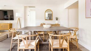 A dining area with a large rectangular table, six chairs, a bowl on the table, a mirror above, and a television on the wall. - 6BR Villa w/ Pool, King Beds & Top Amenities! (Miami)