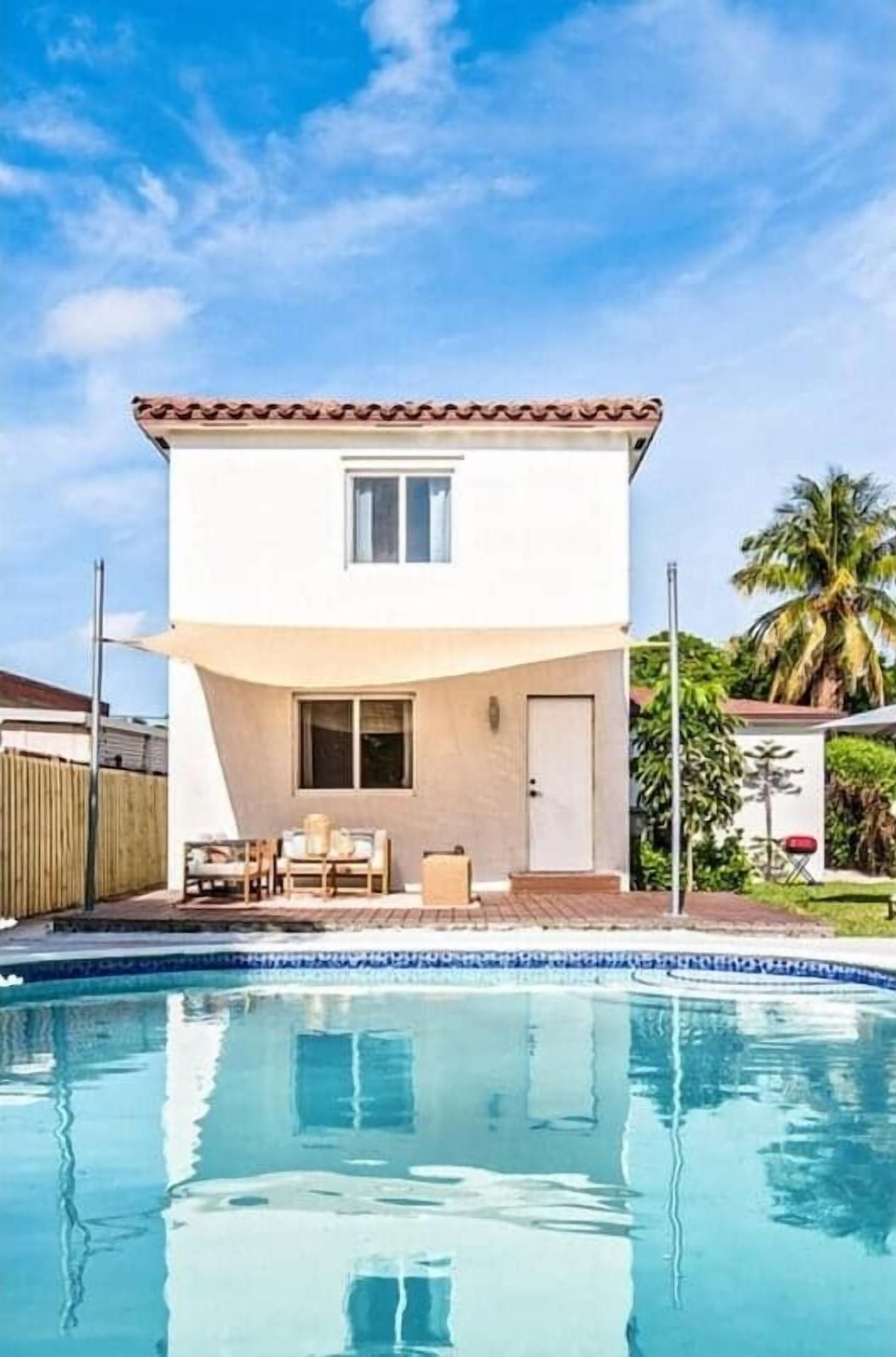 A two-story house with a swimming pool in front.