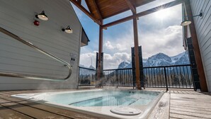 A hot tub with a wooden deck and a view of snow-capped mountains. - Skyridge 401 by Canmore Premier (Harvie Heights)