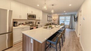 A modern kitchen with a central island, stainless steel appliances, and pendant lighting. - Skyridge 401 by Canmore Premier (Harvie Heights)