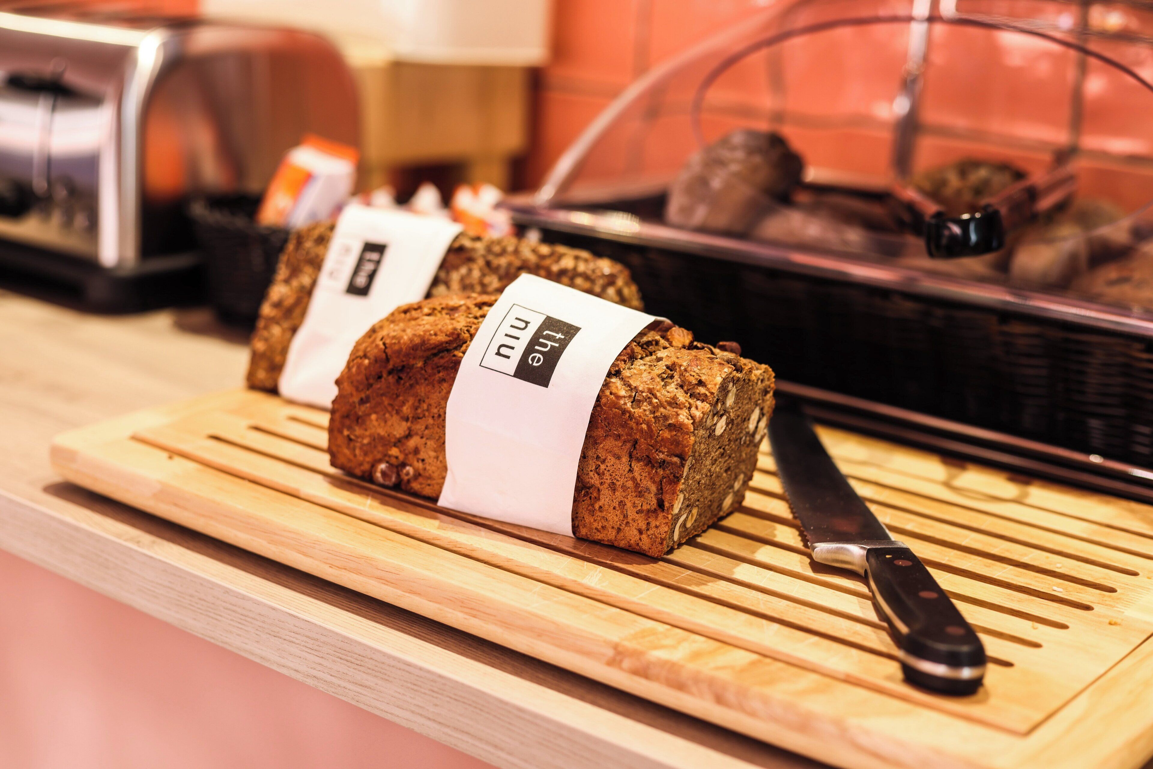 Two loaves of bread on a wooden cutting board with a knife beside them.