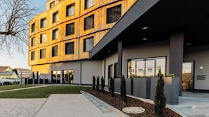 Ein modernes Gebäude mit Holzfassade, großen Fenstern und einem überdachten Eingangsbereich.