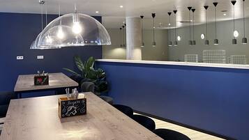Un interior moderno con mesas de madera, iluminación colgante en forma de cúpula transparente y una pared de acento azul.