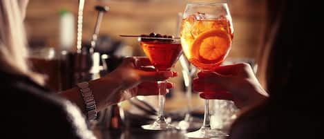Two people holding cocktail glasses with orange slices.