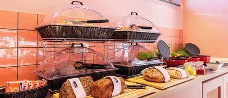 A breakfast buffet with various breads, pastries, and condiments.