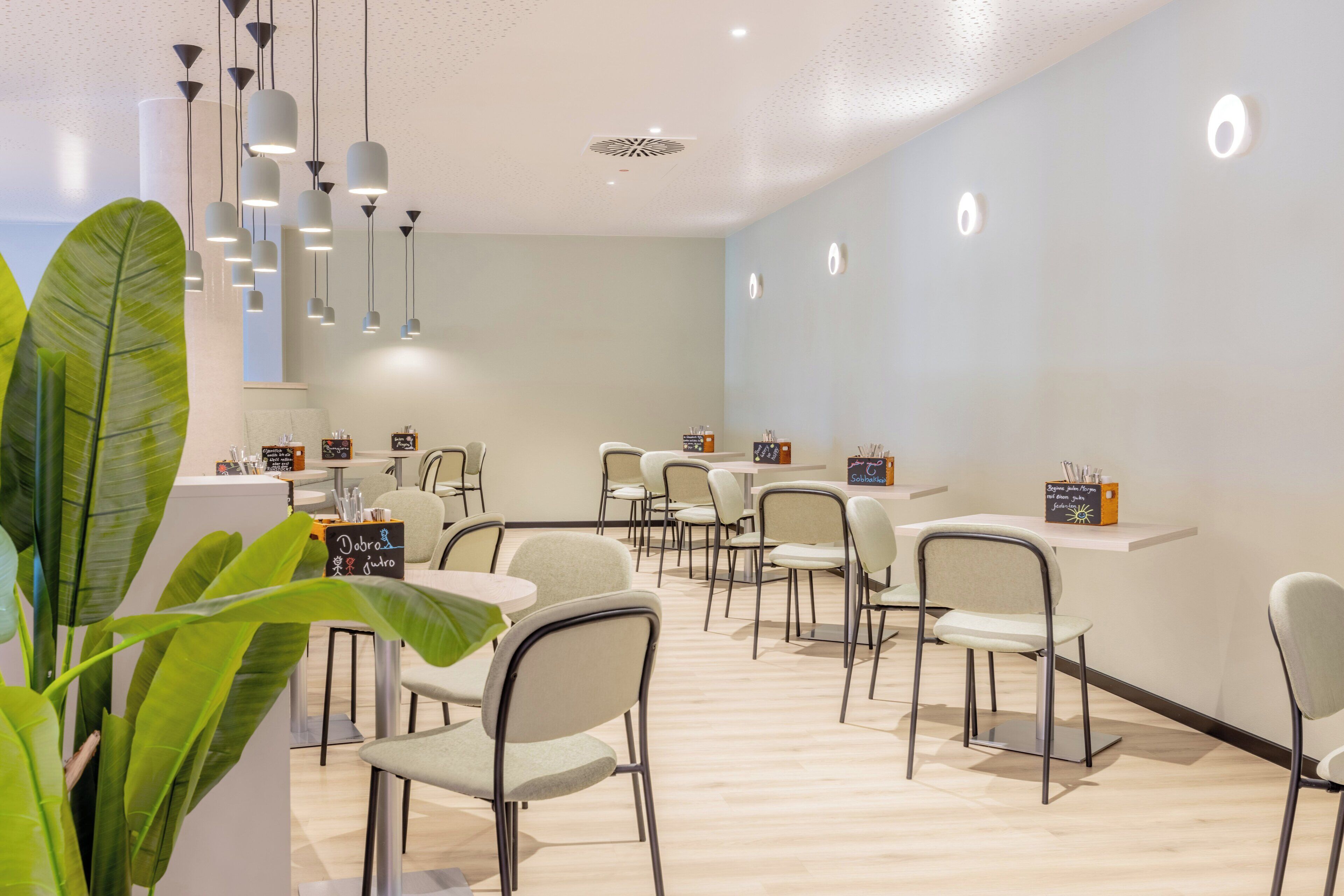 Un interior moderno con mostrador de recepción, varias zonas de estar e iluminación colgante.