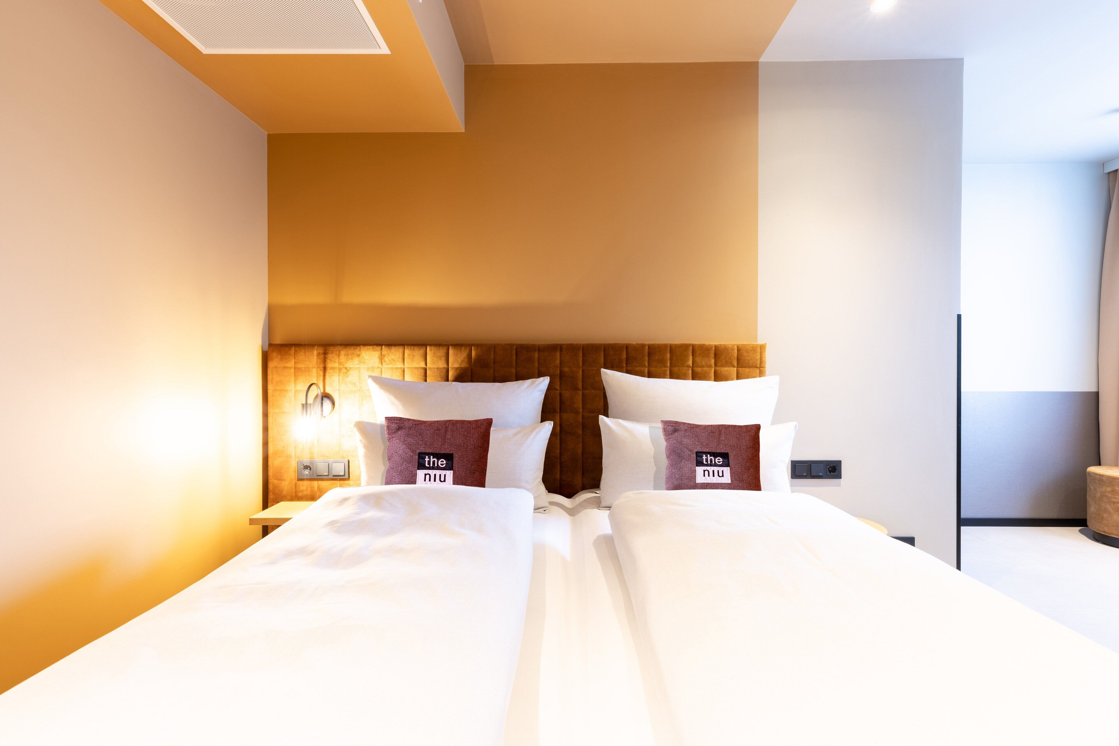 A hotel room with a large bed, a wooden headboard, and a nightstand with a lamp.