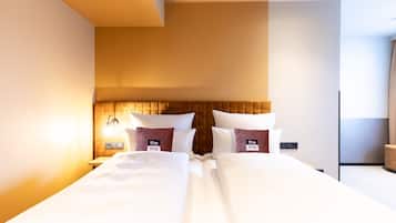 Camera d'albergo con un letto grande, una testiera in legno e un comodino con una lampada.