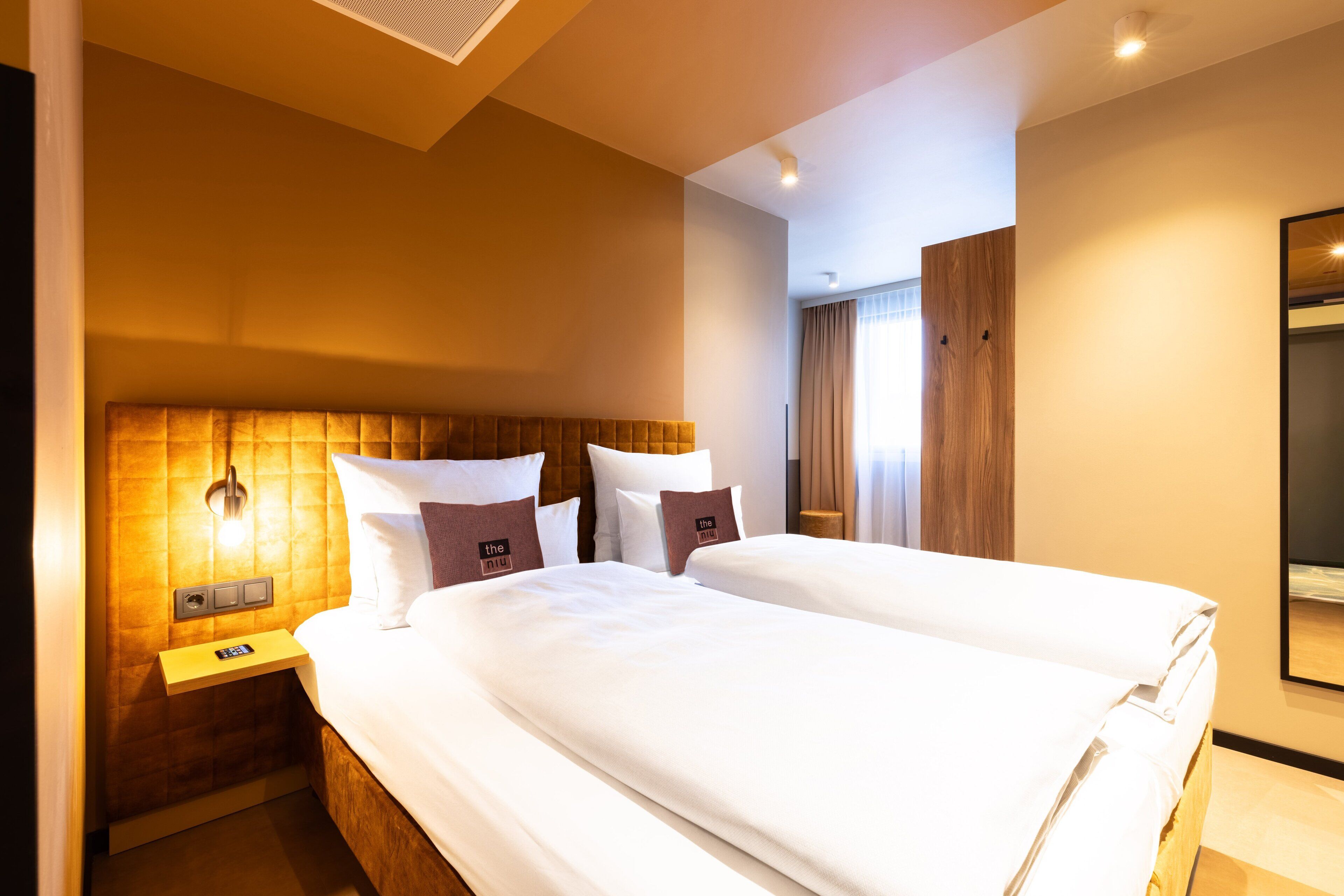 Ein Hotelzimmer mit zwei Betten, einem Nachttisch mit Telefon und einer Wandleuchte.
