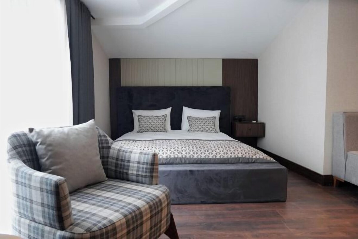 A bedroom with a bed, a chair, a bedside table, and a nightstand.