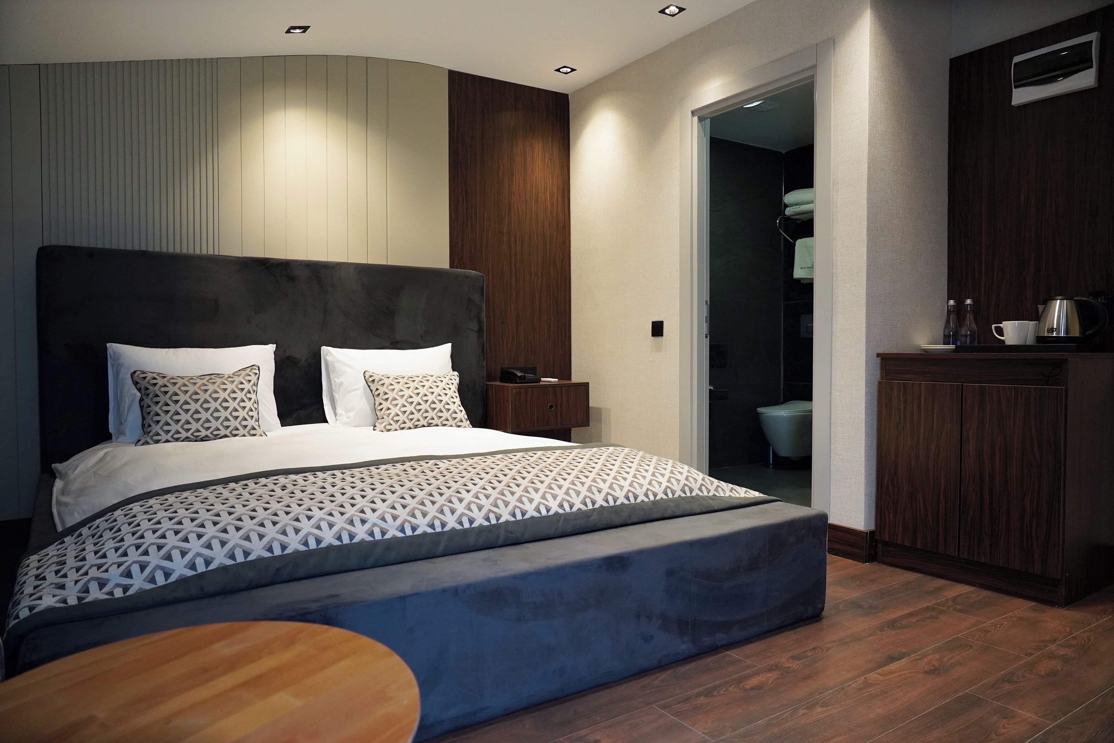 A modern bedroom with a large bed, a bedside table, and a wardrobe.