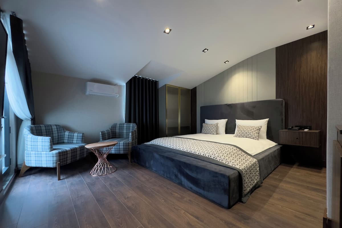 A modern bedroom with a large bed, two sofas, a small table, and a built-in wardrobe.