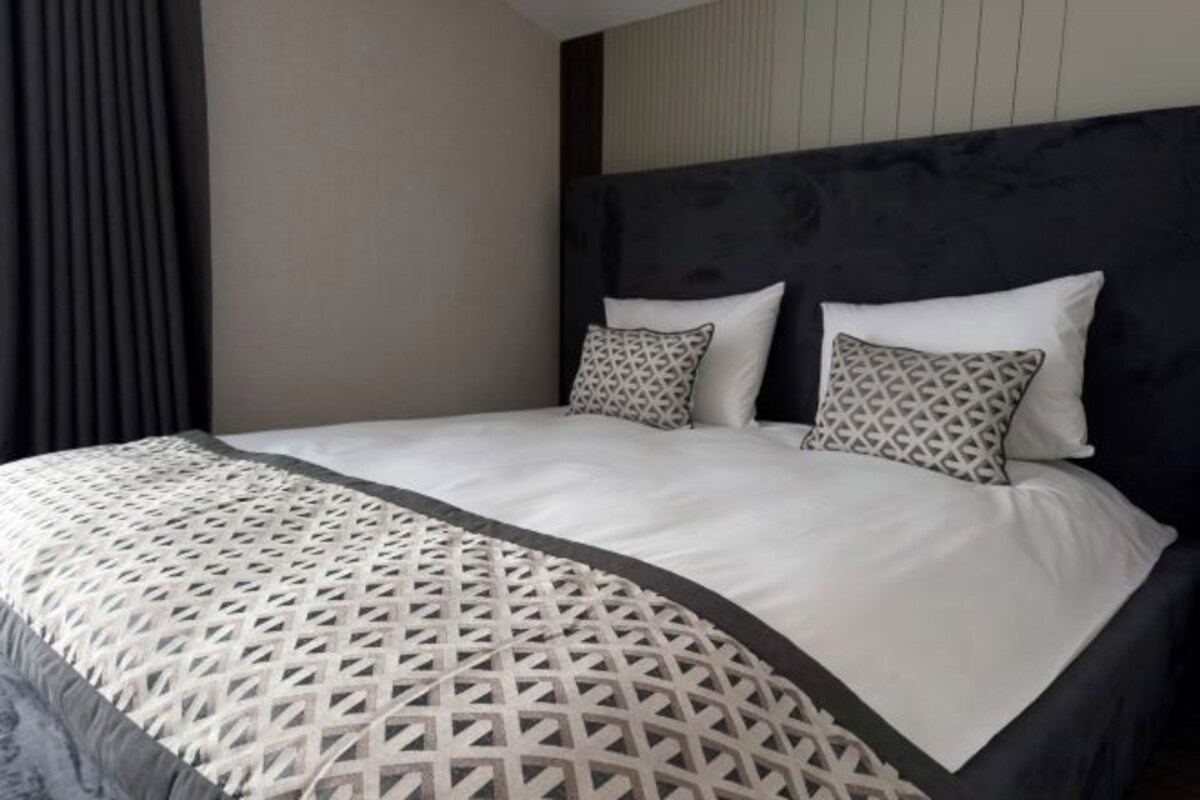 Una cama bien hecha con un edredón estampado y dos almohadas con diseños geométricos.