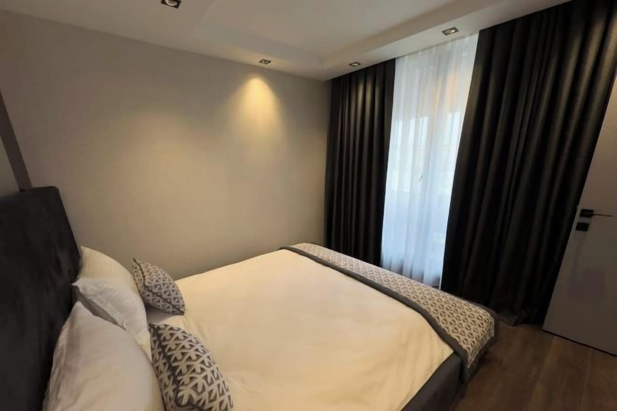A hotel room with a bed, a wardrobe, and a window with curtains.