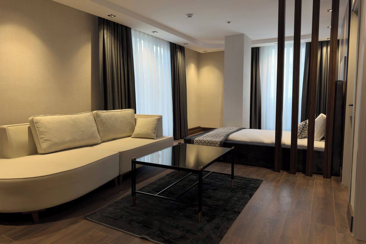 A modern living room with a curved sofa, a glass-top coffee table, and a dark rug.