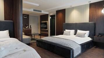 A modern hotel room with a large bed, a smaller bed, a desk, and a wardrobe.