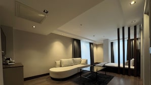 A modern living room with a sofa, a coffee table, and a dining area with a small table and chairs. - Nevizade Avangart Hotel (Istanbul)