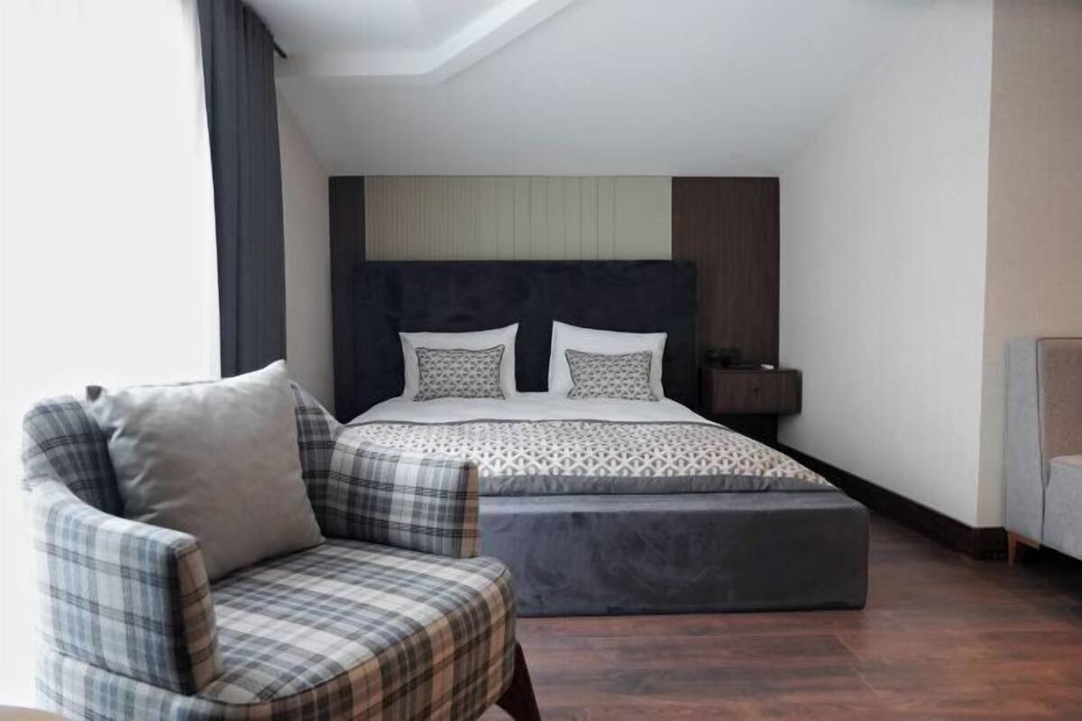 A bedroom with a bed, a chair, a bedside table, and a nightstand.