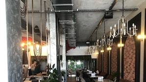 A restaurant interior with a long counter, multiple tables, and hanging chandeliers. - Nevizade Avangart Hotel (Istanbul)