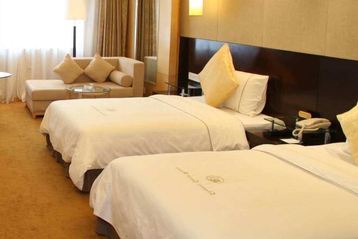 A hotel room with two beds, a sofa, a small table, a lamp, and a telephone.