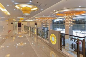 Un intérieur moderne avec un sol réfléchissant, des luminaires circulaires au plafond et une balustrade en verre donnant sur un niveau inférieur.