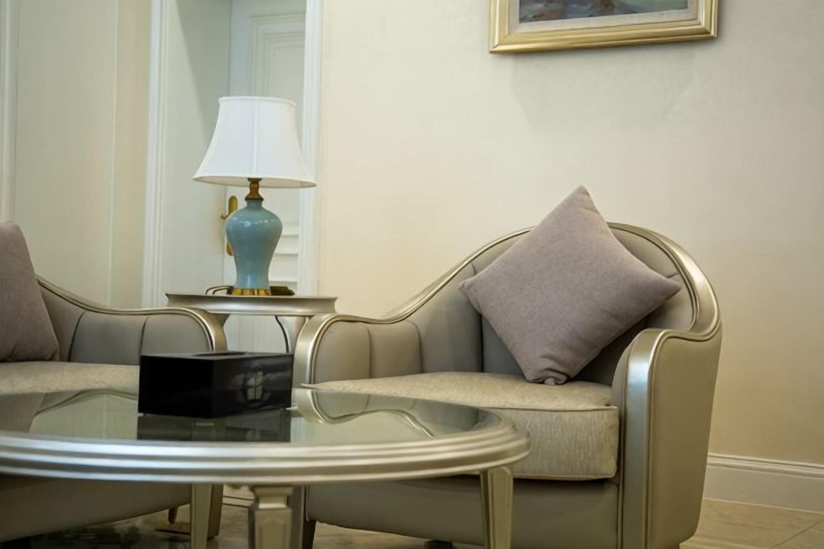 A room with two sofas, a round table, a lamp, and a framed picture on the wall.