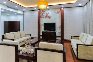 A modern living room with sofas, a coffee table, and a TV. - Grand Shaanxi Hotel (Xi'an)