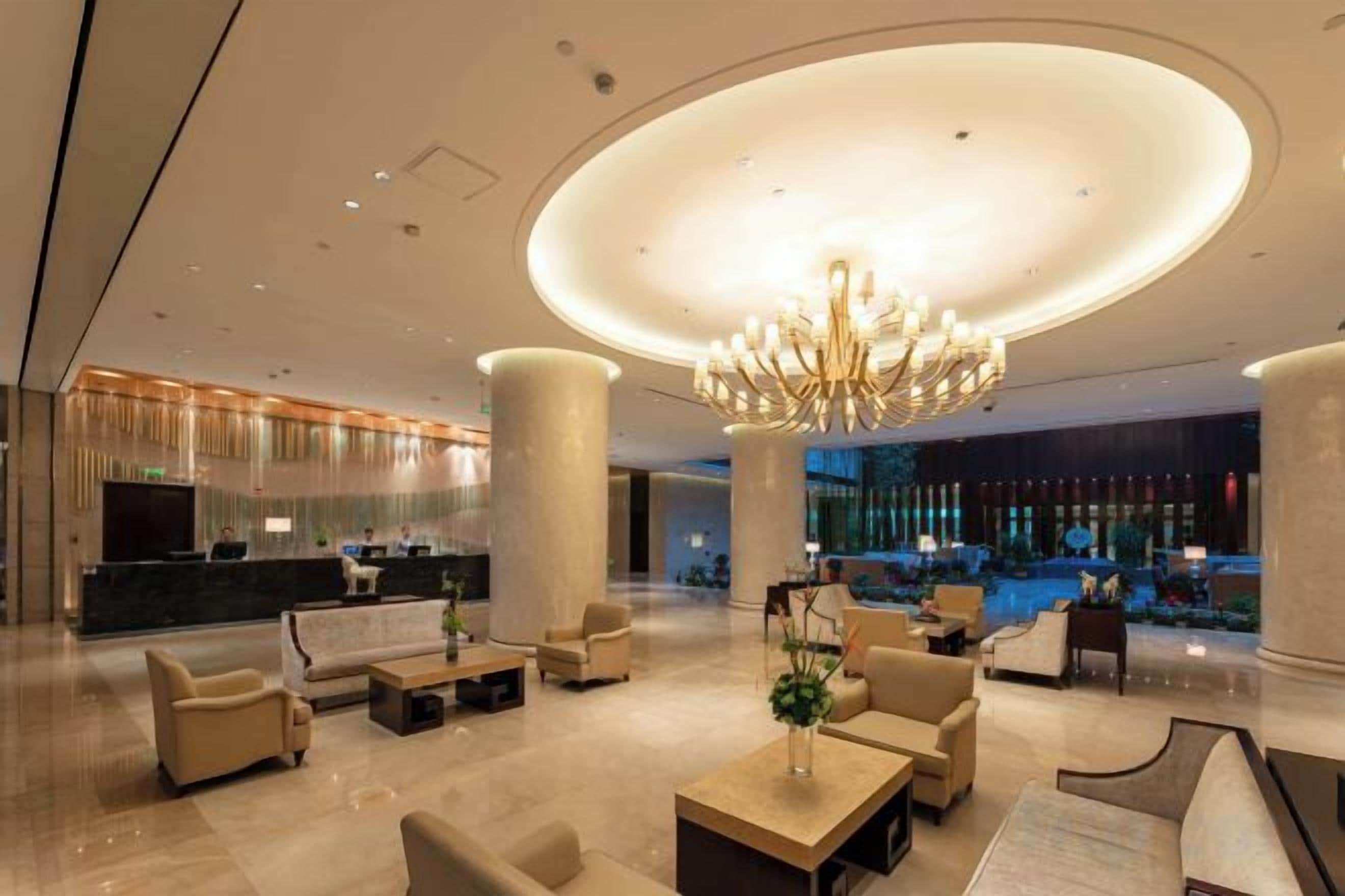 A spacious lobby with a grand chandelier, comfortable seating, and a reception desk.