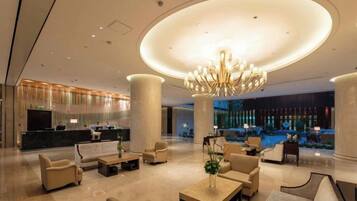 A spacious lobby with a grand chandelier, comfortable seating, and a reception desk.