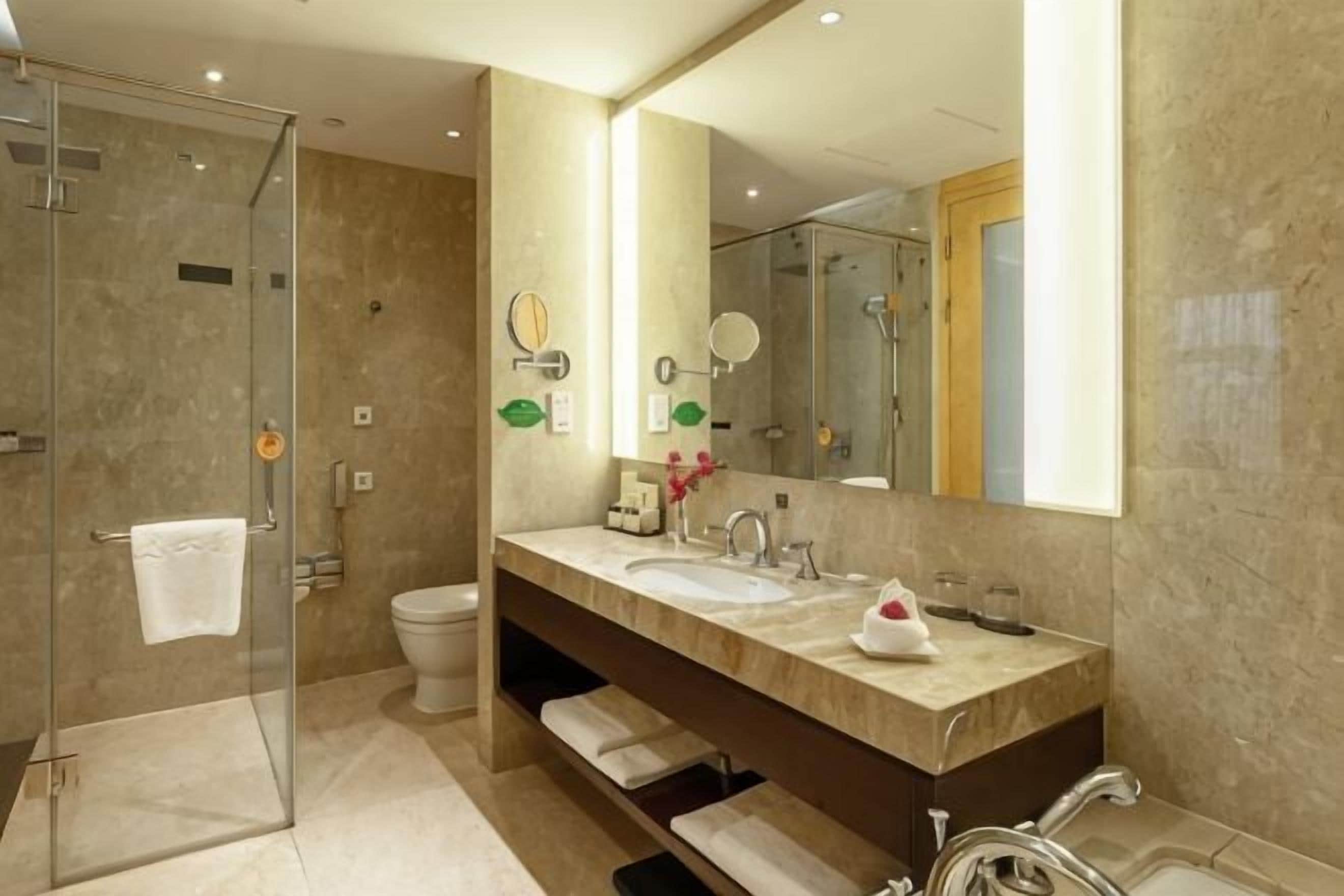 A modern bathroom with a glass shower enclosure, a double sink vanity, and a large mirror.