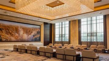 Un salón de conferencias con una pantalla grande, diversas disposiciones de asientos y una araña de cristal.