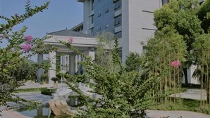 Un hotel con jardín, un estanque y una zona cubierta.