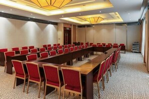 A conference room with a long table and red chairs, a patterned carpet, and a modern ceiling design. - Grand Shaanxi Hotel (Xi'an)
