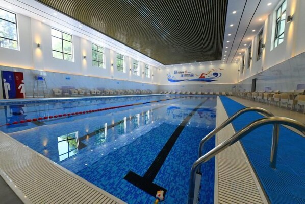Una piscina interior con carriles de natación, una silla de socorrista y un gran mural en la pared.