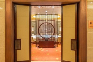 L’entrée d’un hôtel, avec un comptoir d’accueil, un espace repas et un sol recouvert de moquette.