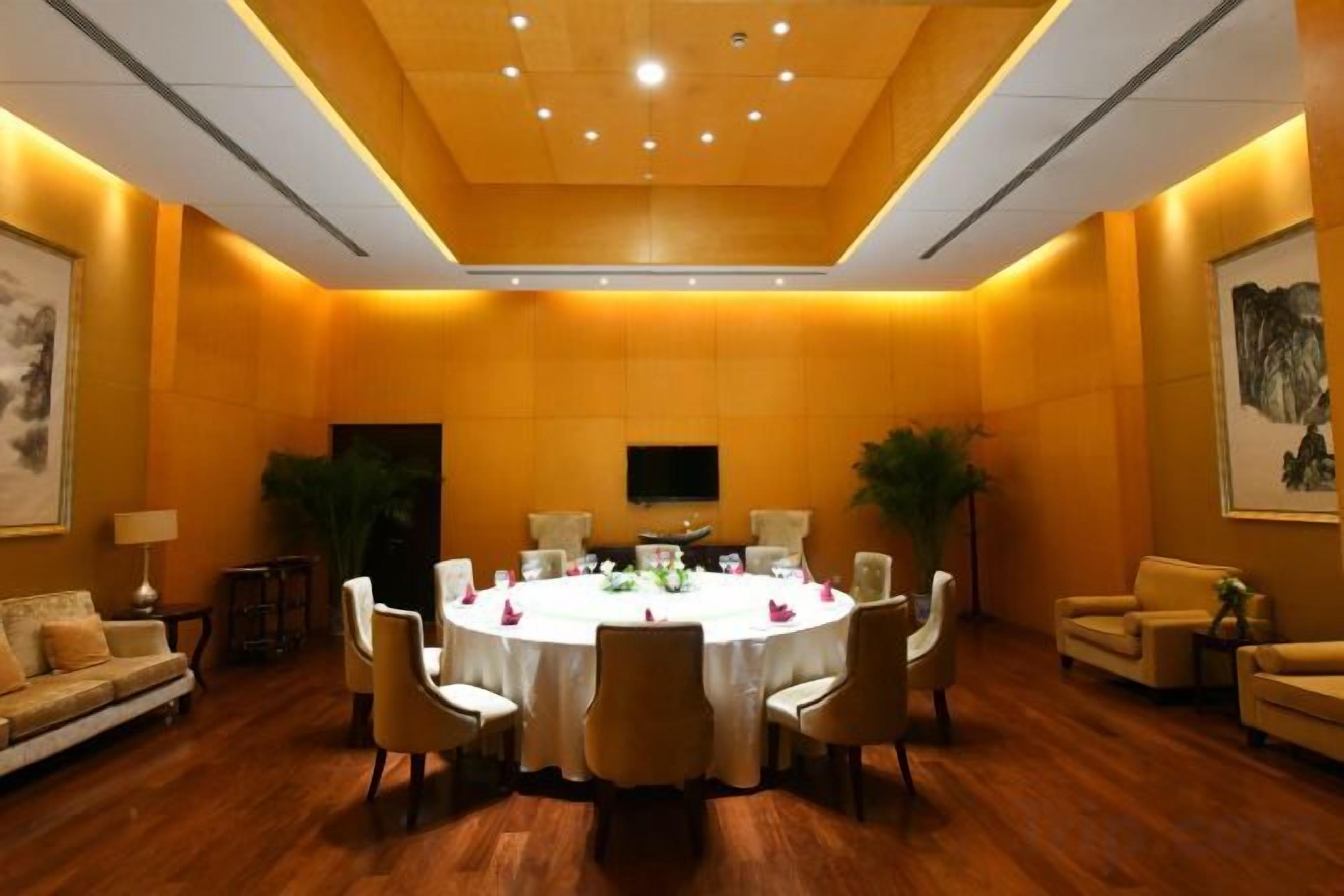 A conference room with a round table, chairs, and a flat-screen TV on the wall.