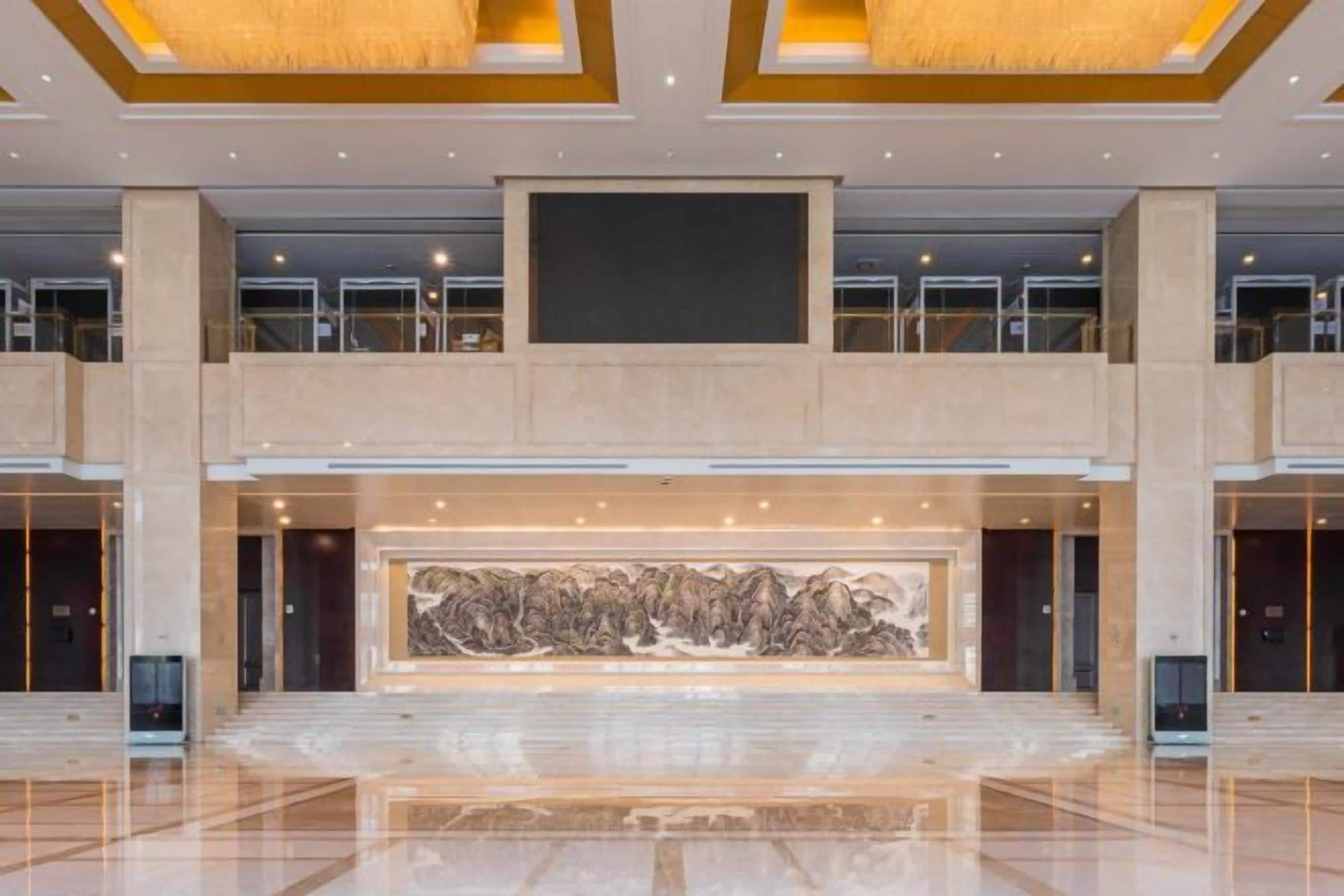 A spacious lobby with a large central artwork, multiple floors, and a modern design.