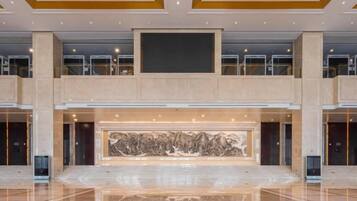A spacious lobby with a large central artwork, multiple floors, and a modern design.