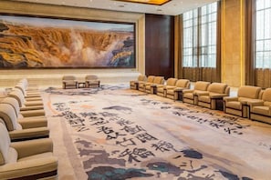 A conference room with a large screen, rows of chairs, and a carpet with calligraphy. - Grand Shaanxi Hotel (Xi'an)