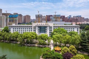 A modern building with a central courtyard, surrounded by trees and a body of water. - Grand Shaanxi Hotel (Xi'an)